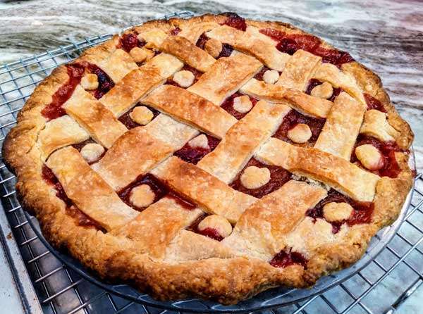 Cranberry apple pie. Red filling shows through a wide lattice top crust with small "buttons" of crust in the gaps.