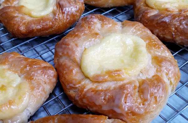 Round danish with cream cheese filling in the center, glistening with freshly applied glaze.
