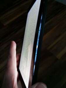 Side view of a small tablet. The screen is separated from the body and blue light shines from the open seam.
