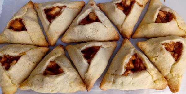 Rows of small pastries shaped into triangles with a bit of apple-cinnamon filling peeking out a window in the center.