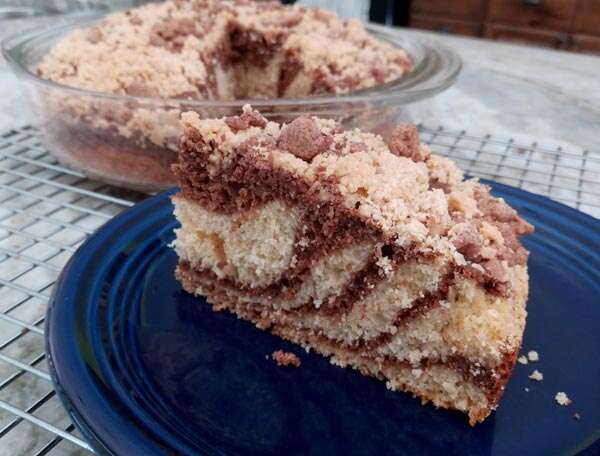 Slice of coffee cake with stripes of peanut butter and chocolate baked in, topped with peanut butter and chocolate crumbles.