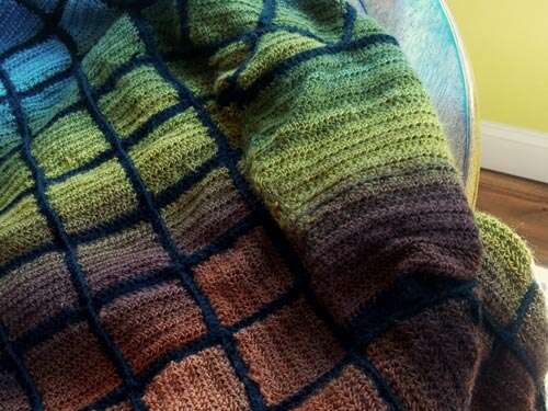 Closeup of a sweater sleeve with gradient color from green to gold to dark brown. Unlike the body to which it is attached, the sleeve has no patchwork seams.