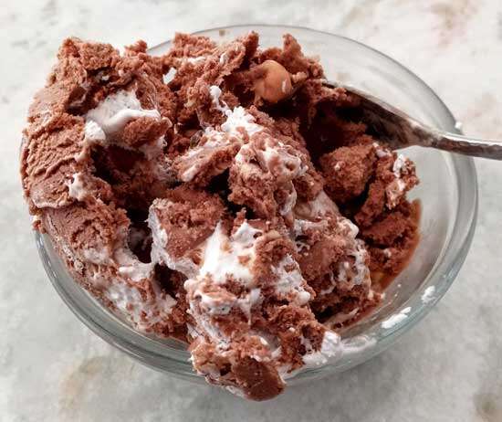 A small bowl of chocolate ice cream with a generous amount of marshmallow fluff swirled in.