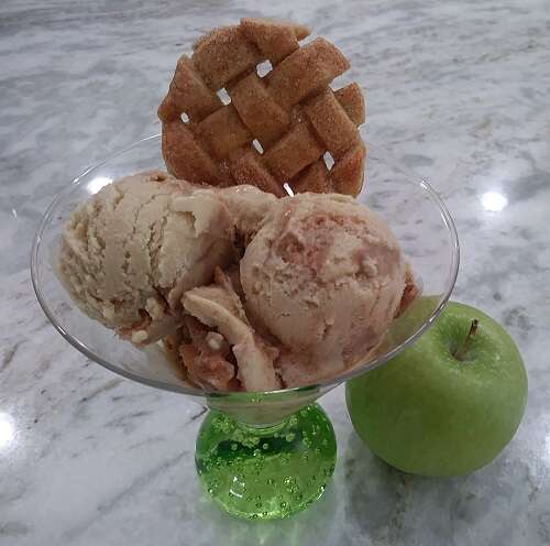 Scoops of apple cinnamon ice cream in a martini glass with a lattice pie crust cookie for garnish