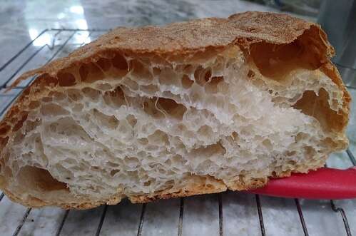 Oblong loaf of bread cut open to reveal thin-walled bubbles like a wasp nest